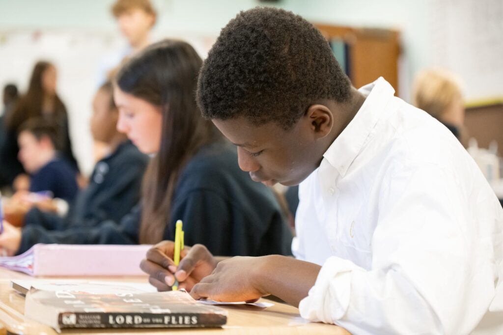 boy at desk holding pencil